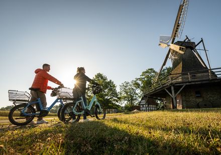 Twee fietsers kijken bij zonsondergang naar een molen