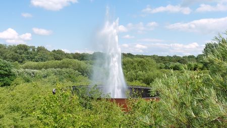 Waterfontein bij de waterkrater in het Aqua Magica Park, omringd door bomen