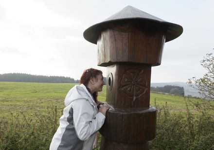 Vrouw kijkt door houten figuur