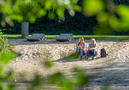 Twee vrouwen zitten op een zanderig terrein