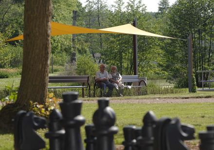 Twee mensen zitten op een bankje in de schaduw van de spa-tuinen