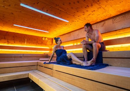 Twee personen zitten in een modern verlichte sauna