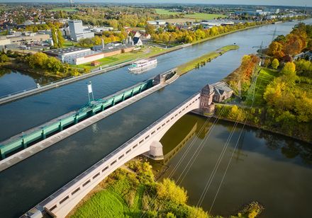 De foto toont het kruispunt van waterwegen van bovenaf. Een schip van de Mindener Fahrgastschiffahrt vaart op het Mittellandkanaal.