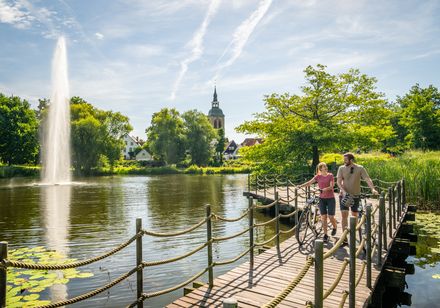 Een stel met fietsen wandelt over een steiger aan het Emsmeer. 