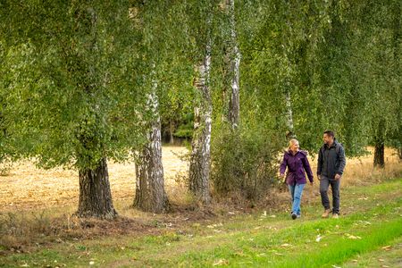 Twee mensen lopen over een veldweg, met links van hen bomen