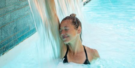 Vrouw onder een waterstraal in het zwembad