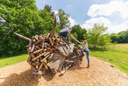 Twee mensen klimmen op een houten bizonbeeld