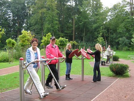 Mensen sporten op toestellen in de Tuin der Generaties