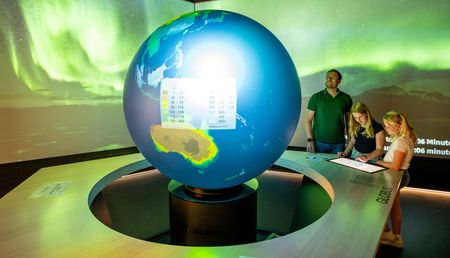 Vader met kind voor wereldbol in het klimaatbeleveniscentrum