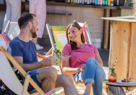 Een man en een vrouw zitten in ligstoelen en kijken elkaar aan.