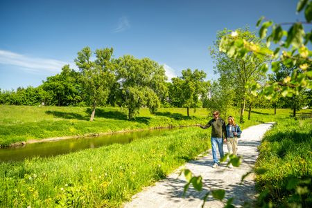 Twee mensen wandelen langs de Werre in een groen parklandschap