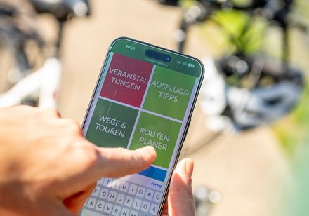 Persoon houdt mobiele telefoon in zijn hand en wijst met zijn andere hand naar het scherm