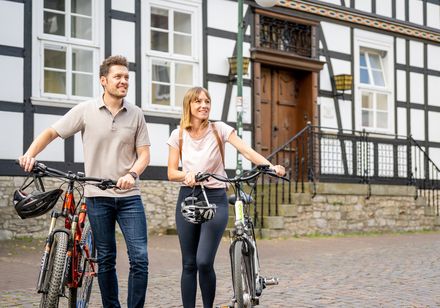Twee mensen op de fiets voor een vakwerkhuis