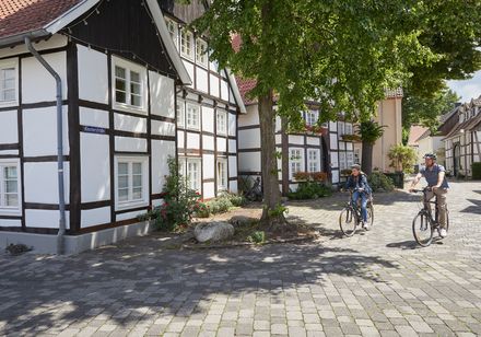 Twee mensen op de fiets, met daarnaast vakwerkhuizen