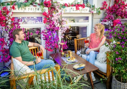 Twee personen genieten van een drankje op een met bloemen versierd terras