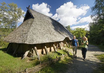 Mensen naast het longhouse in het openluchtmuseum Oerlinghausen