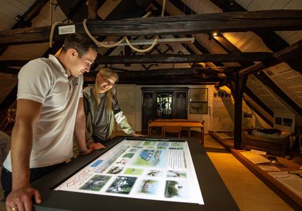 twee mensen kijken naar de flikkerende beelden in het Heimathaus
